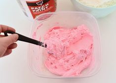 someone is spreading pink icing in a bowl