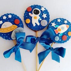 three blue lollipops with space themed decorations on them, tied together and sitting next to each other