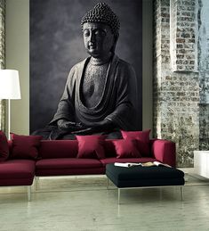 a large buddha statue sitting on top of a red couch in front of a black and white wall