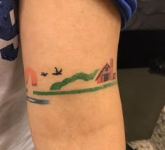 a woman's arm with a small tattoo on it that has birds flying over the water