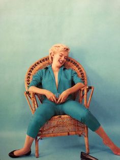 a woman sitting in a wicker chair with her legs crossed and mouth wide open