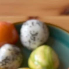 a bowl filled with different types of fruit on top of a wooden table next to an orange