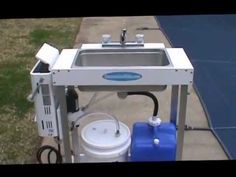 a small sink sitting on top of a sidewalk next to a blue and white bucket