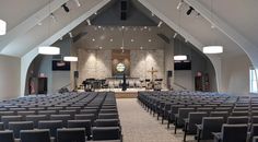 an empty church with rows of chairs facing the front and back, lights hanging from the ceiling