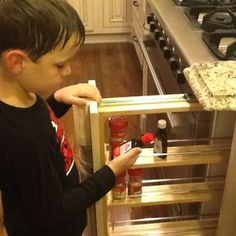 a young boy is opening the oven door to check out his new cooking utensils