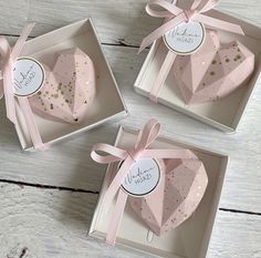 three pink heart shaped boxes with gold confetti on them