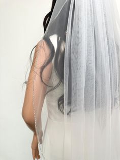 a woman wearing a wedding veil and holding her hand on her shoulder