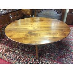 an oval wooden table on top of a rug in a room with other furniture and accessories