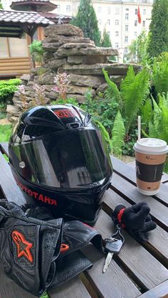 a motorcycle helmet, gloves and coffee sit on a picnic table