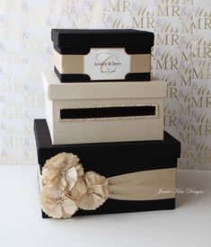 three tiered boxes are decorated with flowers and ribbons on the top one is black, white, and gold