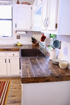 a kitchen with wooden counter tops and white cabinets