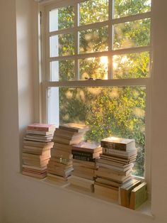 a stack of books sitting on top of a window sill