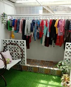 a room filled with lots of clothes hanging on the wall and green grass in front of it