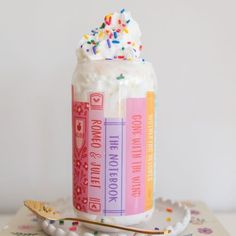 a jar filled with whipped cream and sprinkles on top of a table