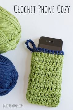 there is a cell phone in a crochet case next to some balls of yarn