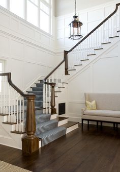 a living room filled with furniture and a stair case next to a white couch on top of a hard wood floor