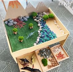 an open box with rocks and plants in it on the floor next to other items