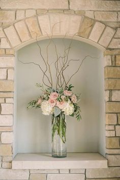 a vase filled with flowers sitting on top of a mantle