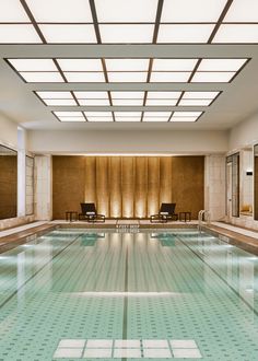 an indoor swimming pool with chairs and mirrors