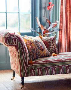 a couch with colorful pillows on it in front of a window