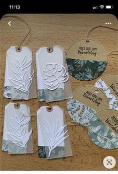 four tags with leaves on them sitting on top of a wooden table next to each other