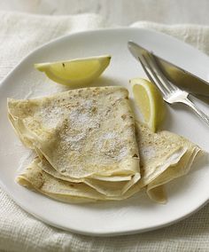 a white plate topped with quesadillas next to a knife and lemon wedges