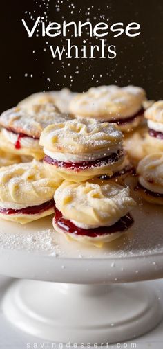 a white cake plate topped with cookies covered in powdered sugar and jelly toppings