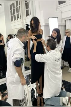 a group of people standing in front of a mirror with one person adjusting the woman's dress