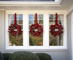 two wreaths are hanging on the windowsill