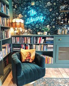 the library is full of books and has a blue chair with a yellow pillow on it