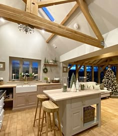 a large open kitchen and living room with wooden beams on the ceiling, hardwood flooring