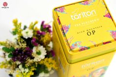 a yellow tea box sitting next to a bouquet of flowers