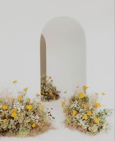 two vases filled with yellow and white flowers next to an arch in the wall