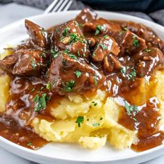 a white plate topped with mashed potatoes covered in gravy