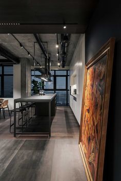 an industrial style kitchen and dining room are featured in this image, while the painting is framed on the wall