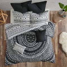 a bed with black and white comforter on top of it next to a wooden floor