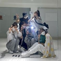 a group of young people posing for a photo in front of a mirror with their hands up