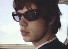 a man wearing sunglasses sitting in the back seat of a car with his head turned to the side