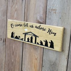 a wooden sign that says come let us adore him with the nativity scene