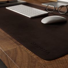 a computer desk with a mouse, keyboard and glasses on it in front of a monitor