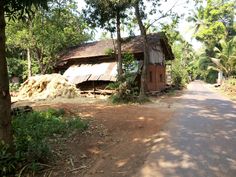 a dirt road next to a wooden shack