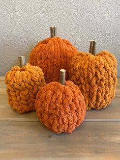 four knitted pumpkins sitting on top of a wooden table