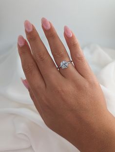 a woman's hand with a diamond ring on top of her finger, against a white background