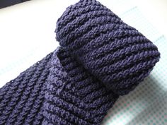 a purple knitted tie laying on top of a table