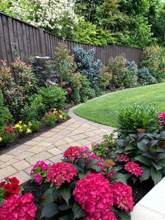 a garden filled with lots of flowers next to a wooden fence