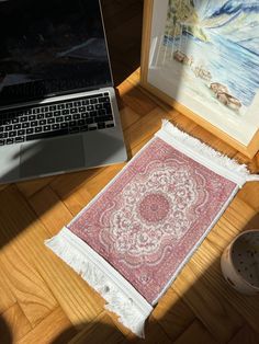 a laptop computer sitting on top of a wooden floor next to a rug and bowl