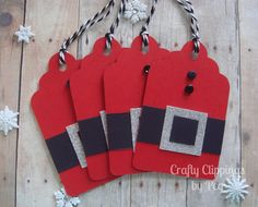 four red and black christmas tags hanging from string on wooden background with snowflakes