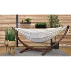 a white hammock sitting on top of a wooden stand next to a potted plant