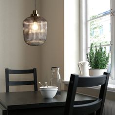 a dining room table with two chairs and a bowl on it next to a window