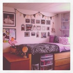 a bed room with a neatly made bed and lots of pictures on the wall above it